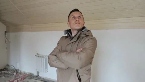 A man stands in the middle of an empty room ready for renovation Stock Footage 139495131