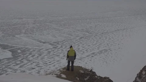 A man stands on a mountain against the background of Lake Baikal covered with 库存影片 153605304