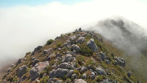 Man stands on mountain peak as drone flies 360 above him through the clouds Stock Footage 128274921