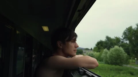 Man stands near the open window of a moving train leaning on the window sill Vídeos de archivo 269511196