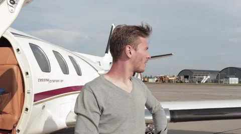 Man Stands Next to a Private Plane on a Background of a Passing Passenger Plane Stock Footage 67184537