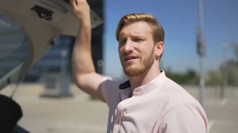 Man stands by open trunk of car in parking lot and have conversation Video stock 83613213