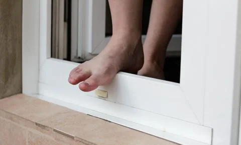 A man stands in an open window. The man wants to jump out of the window. Feet Stock-Fotos