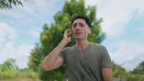 Man stands outdoors, sweating, holding phone to ear Vidéo 345216468