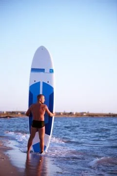 A man stands with a paddleboard on the seafront Stock Photos