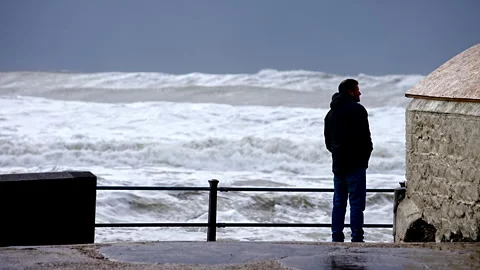A man stands on a pier looking out at the ocean Stock Footage 298264298