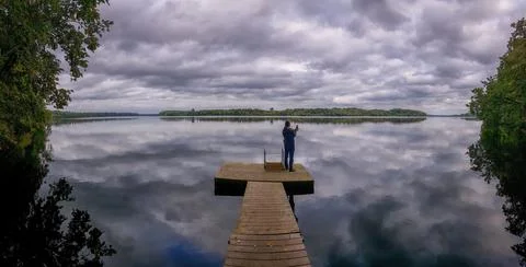 Man stands on the pontoon of the river Stock Photos