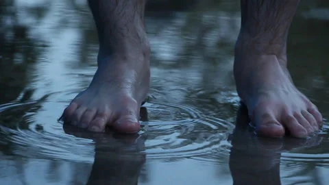 Man stands in a puddle after the rain with bare feet Stock Footage 107987800