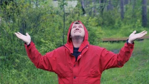 A man stands in the rain and opens his arms to the side against the background Stock Footage 112004501