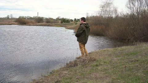 A man stands by the river and fishes 스톡 동영상 153891053