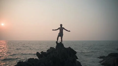 A man stands on a slip during sunset and gently raises his hands. Video stock 234020887