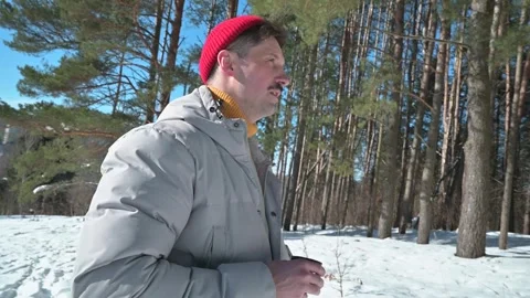 A man stands in a snow-covered forest, sipping from a can while surrounded by Stockbeeldmateriaal 337101815