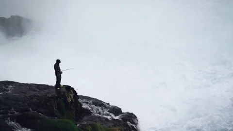 A man stands on a stone next to a waterfall Stock Footage 142123545
