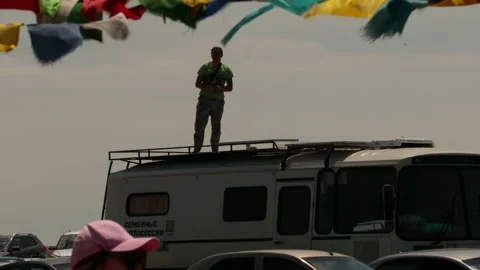 Man stands on top of a camper van in Kalmikia. Colorful flags flutter in the Stock Footage 318538000