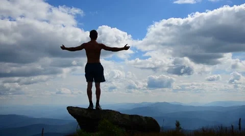 Man stands on top of a mountain with open hands. Stock Footage 68964030