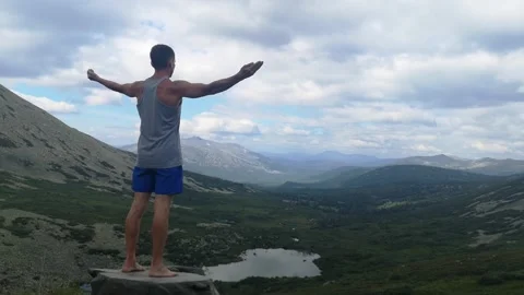 Man stands on top of a mountain with open hands. Stock Footage 137744584
