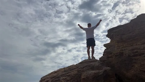 Man stands triumphantly on rocky summit. Concept of motivation and achievement Vídeo Stock 336596672