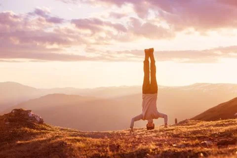 Man stands upside down at mountain sunset Stock Photos