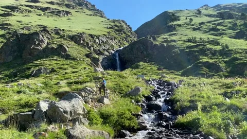 A man stands at a waterfall in the mountains Stock Footage 135334388