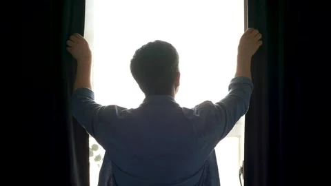 Man stands at window and closes curtains back view. Stock Footage 315021438
