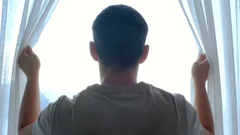 Man stands at window and opens curtains back view. Stock Footage 232444308