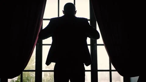 Man stands at the window and puts on a jacket Stock Footage 161721994