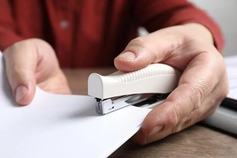 Man stapling papers at wooden table, closeup 写真素材