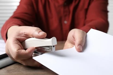 Man stapling papers at wooden table, closeup 写真素材