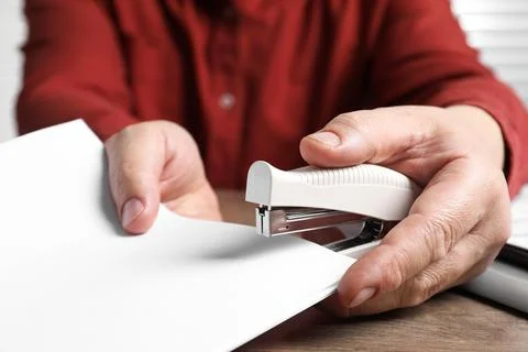 Man stapling papers at wooden table, closeup 写真素材