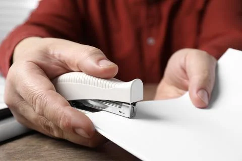 Man stapling papers at wooden table, closeup 写真素材