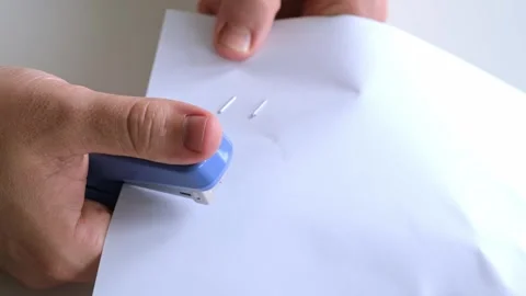 Man stapling sheets of paper with a blue office stapler. Males hands hold a Stock Footage 321862083