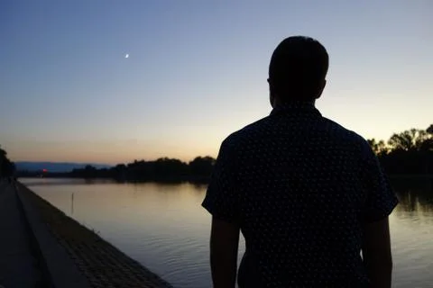 Man staring in distance in front of rowing channel at sunset time Stock Photos