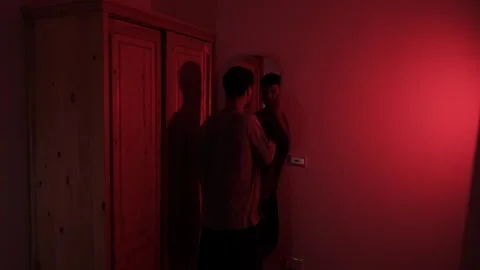 Man staring at himself in a mirror and repeatedly slapping his face, expressing Видео 347301264
