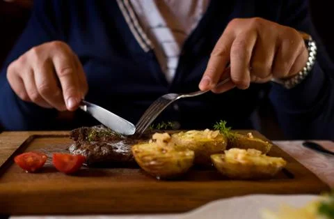 Man started eat medium roasted veal steak . Hands close-up view. Stock Photos