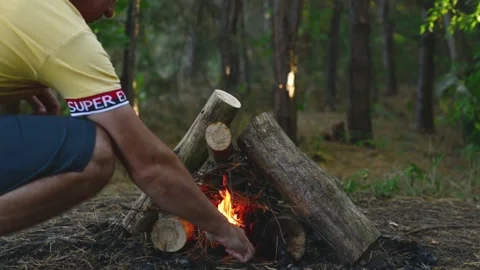 Man starting a campfire in the forest igniting fire with wood. Stockbeeldmateriaal 345121997