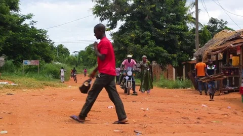 Man starting his bike while other villagers busy in their chores Stock Footage 77446299