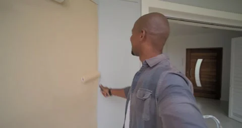 Man starting repainting entry wall with roller, showing brush and bucket, Stock Footage 337160627