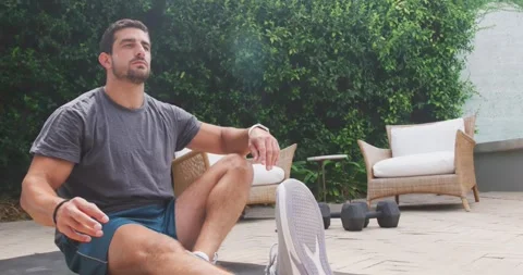 Man starting toe reach, warming up with leg lifting on patio in sportswear with Video stock 336784879