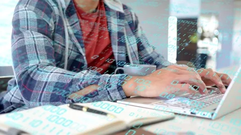 Man starting by typing on laptop, checking notebook, binary overlay over hands Stock Footage 333893874