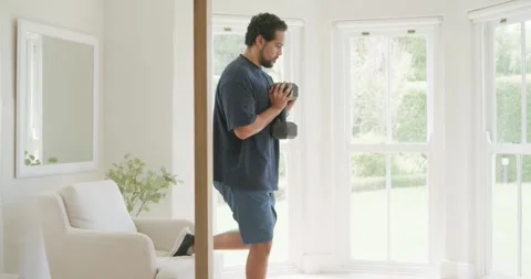 Man starting workout doing split squats with weights on chair at home for Stock Footage 336716515