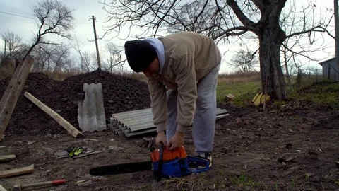 A man starts a chainsaw, preparing for construction work Stock Footage 120253345