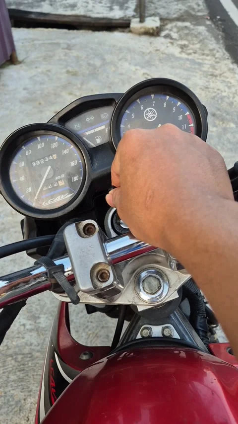 A man starts a red Yamaha V-Ixion motorcycle by inserting the key Stock Footage 339657871