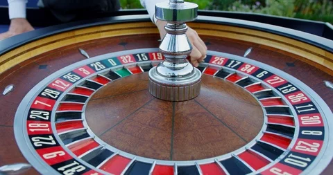 Man starts to spin the roulette wheel, as he throws the ball in circular Stock Footage 121742822