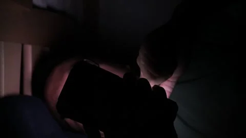 A man is staying up late looking at his phone, an unhealthy lifestyle. Видео 310253362