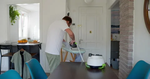 A man steaming a shirt in a dining room: Stock Footage 344308761