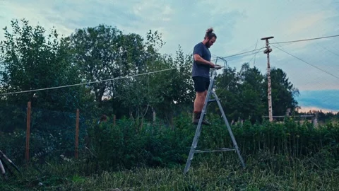 A Man With A Steel Step Ladder Working In A Yard. Static Shot Stock Footage 337536389