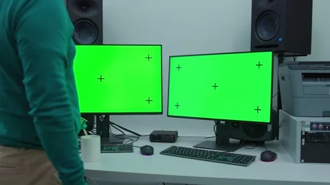 A man step in the scene with two computer monitors are on a desk with a green sc Stockbeeldmateriaal 270359750