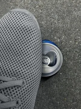 A man stepped stepping compressed cans on cement ground Foto stock