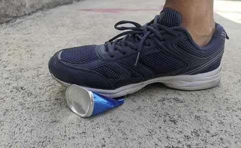 A man stepped stepping compressed cans on cement ground Foto stock