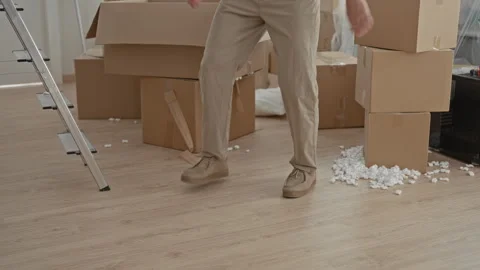 Man stepping among cardboard boxes and scattered packing peanuts while carr.. Stock Footage 339178873